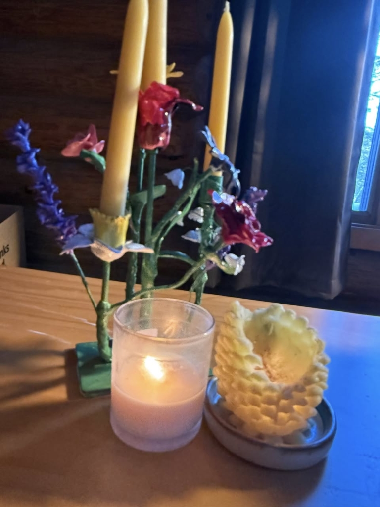 An arrangement of candles on a table with plastic flowers.