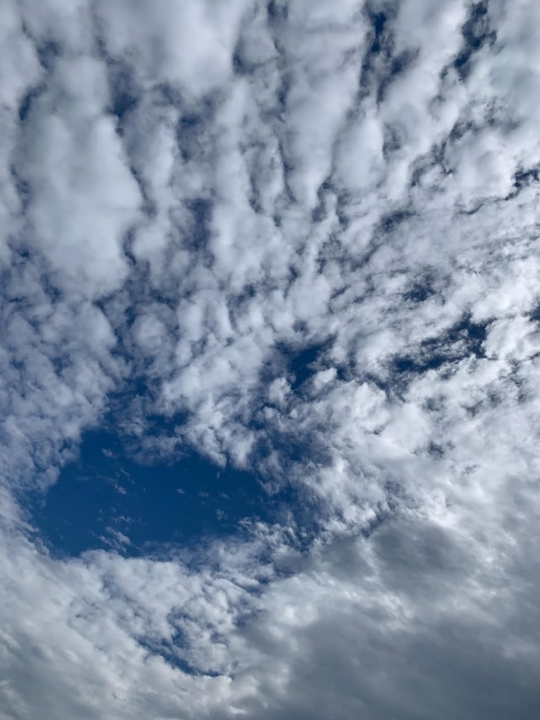 Photo of clouds below a deep blue sky.