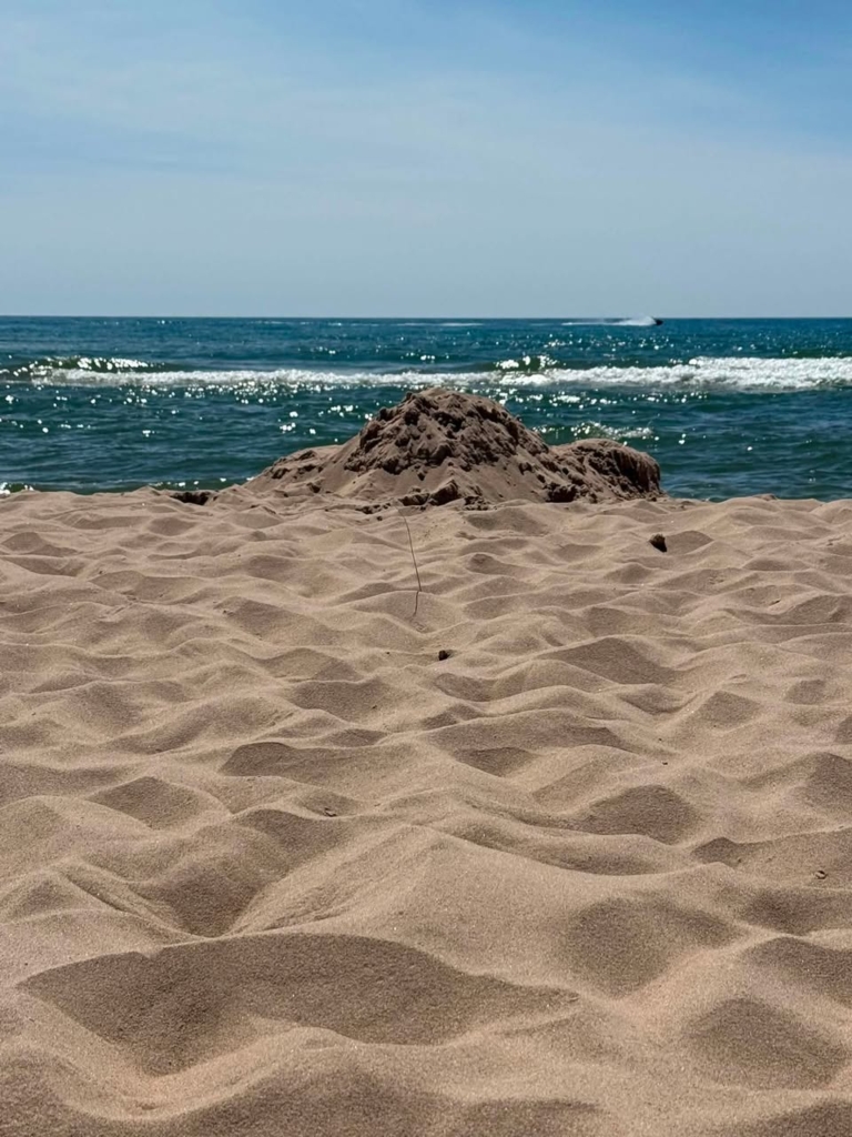 Image of beach with a small mound of sand in front of Lake Michigan on a summer day in Michigan.