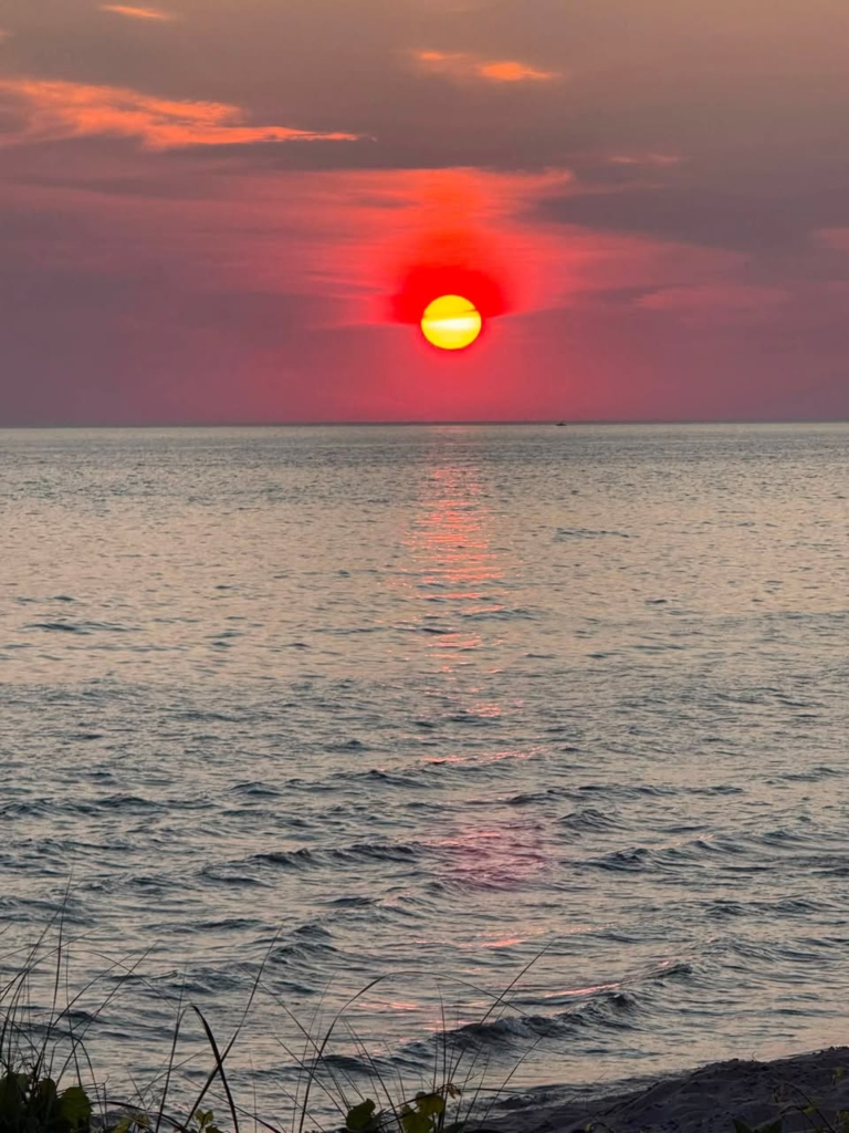 Image of Lake Michigan at twilight with the sun setting on the horizon during a summer evening in Michigan.